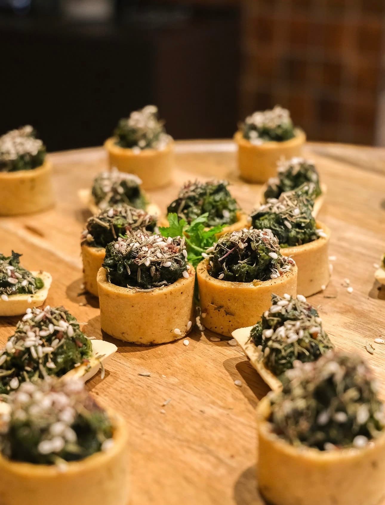 Tartelettes aux épinards et herbes présentées sur un plateau en bois