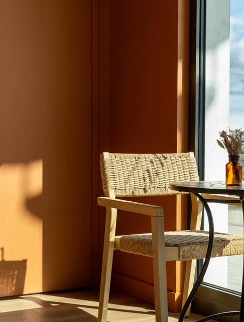 Chaise en bois et rotin baignée de lumière près de la baie vitrée