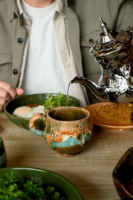 Moment de partage autour d'un repas : thé versé dans une tasse en céramique