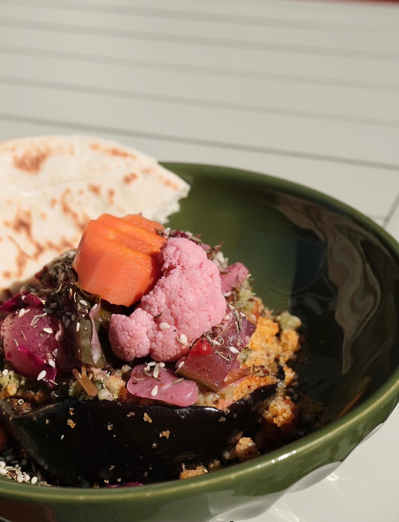 Plat signature de Parvana : aubergine fondante, légumes marinés et pain plat dans un bol vert