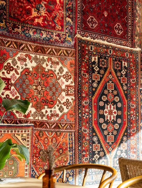 Mur de tapis persans et table dressée dans la salle de Parvana