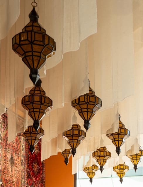 Lanternes et voilages suspendus dans la salle, devant un tapis traditionnel